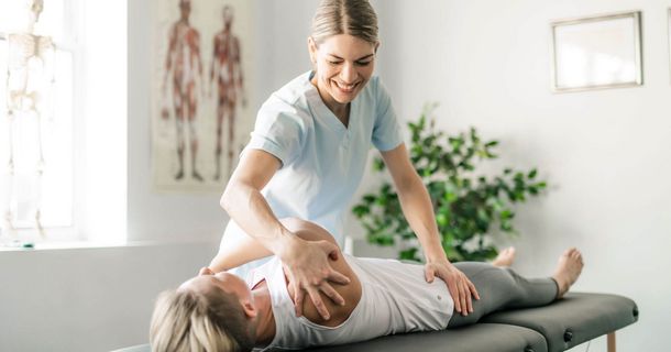 Lächelnde Therapeutin mit Patienten auf der Liege