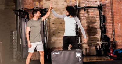 Zwei junge Männer geben sich im Fitnessstudio High Five