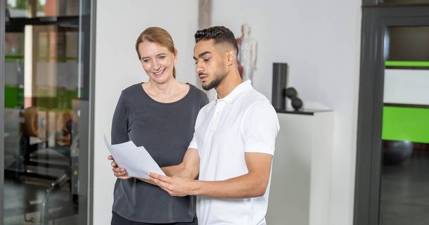 Mann mit Zettel in der Hand erklärt einer Frau etwas