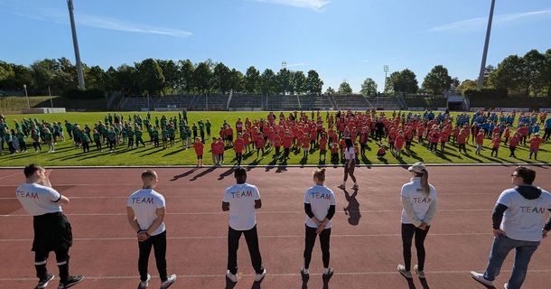 Kinder und Coaches der dba bei der Kinderolympiade in einem Stadion