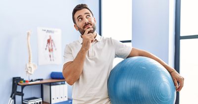 Ein Physiotherapeut hat einen Gymnastikball in der Hand und blickt hoch in die Luft