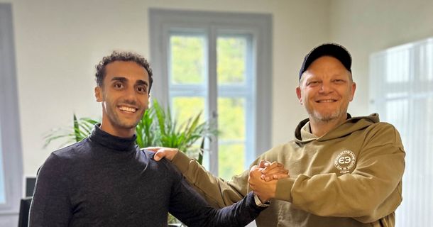 Saleh Edghaym und Marcus Schlosser (v. l.) beim Shake-hands und lachen dabei in die Kamera
