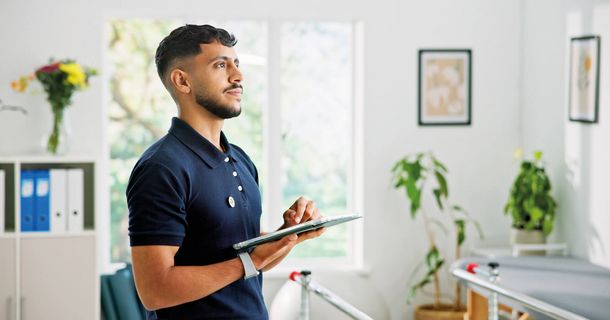 Physiotherapeut mit Tablet in der Hand in einer Praxis