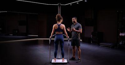 Eine Frau steht während einer Körperanalyse auf einer seca-Messstation, während ein Trainer ihr das Verfahren erklärt.