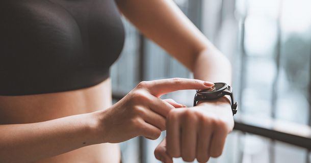 ACSM-Fitnesstrends 2026: Wearables erneut auf Platz 1 Frau im Fitnessstudio prüft ihr Wearable nach dem Training