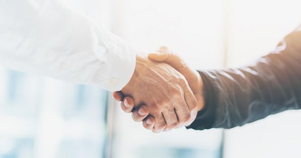 Mitten im Bild ist ein Handshake zu sehen.