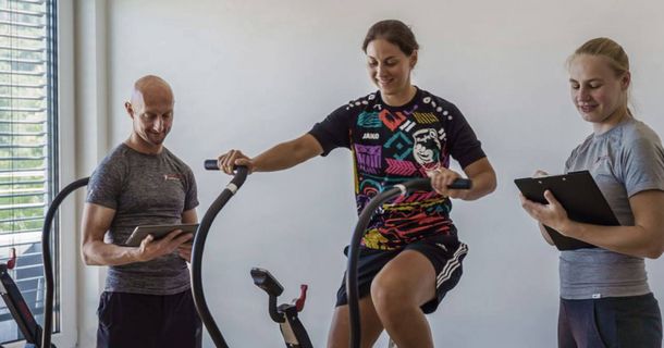 Dr. Björn Haiduk mit Patientin auf einem Indoor-Bike und Trainerin