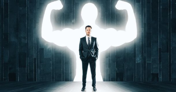Ein Mann im Anzug steht vor einer Wand mit einer starken Person.