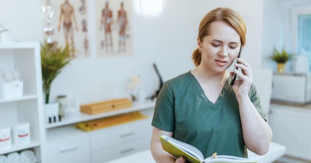 Physiotherapeutin telefoniert in einem Behandlungsraum