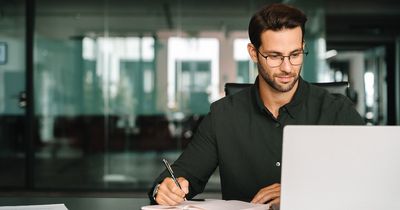 Person sitzt vor einem Laptop und nimmt an einem Webinar teil. Er macht sich Notizen