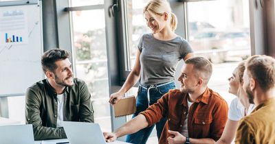 Eine Gruppe an Mitarbeitern im Büro vor einem Laptop