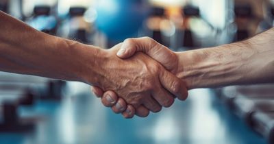 Zwei Menschen schütteln sich in einem Fitnessstudio die Hände. Nahaufnahme. Konzept für eine Geschäftspartnerschaft und Fitness