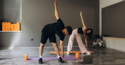 Paar macht Yoga zuhause vor Laptop