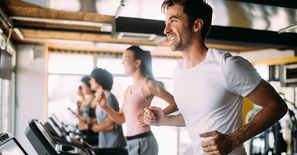 Lächelnder Mann im Fitnessstudio in Laufbewegung