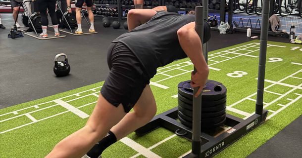 Mann schiebt einen Schlitten beim HYROX-Training