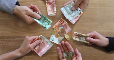 Mehrere Hände mit Geldscheinen und Münzen an einem Tisch