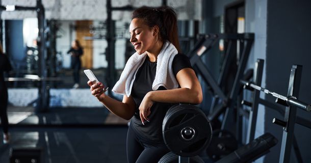 Fitnessstudiomitglied im Fitnesstudio benutzt Smartphone zum chatten