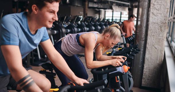 Junger Mann und junge Frau trainieren nebeneinander auf einem Indoor-Rad
