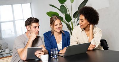 Drei junge Menschen lächelnd vor ihren Laptops