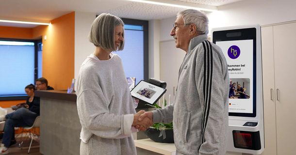 Physiotherapeutin gibt älterem Patienten die Hand