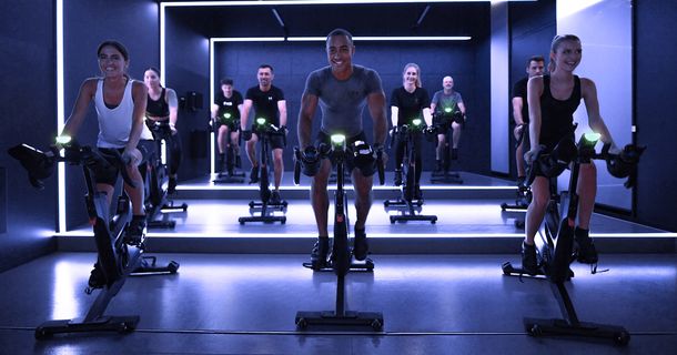Trainer und Fitnessstudiomitglieder auf Indoor Cycles