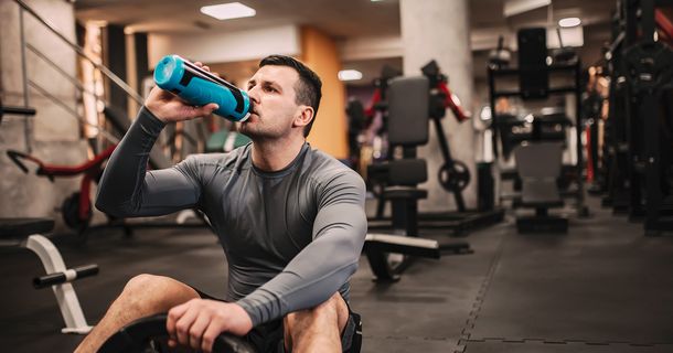 Sportler trinkt nach dem Training im Fitnessstudio