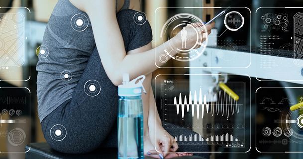 Eine Frau sitzt in Sportkleidung in einem Fitnessstudio, hält ein Smartphone in der Hand und schaut darauf. Vor ihr steht eine blaue Wasserflasche. Das Bild ist mit zahlreichen digitalen Grafiken und Daten-Overlays in Weiß versehen