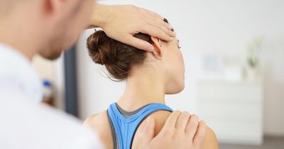 Physiotherapeut dehnt Nacken einer Patientin