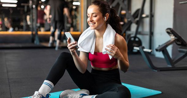 Lachende Sportlerin in Gym mit Smartphone