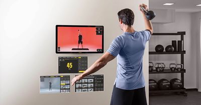 Mann trainiert mit Kettlebell vor Touchscren-Display Visio