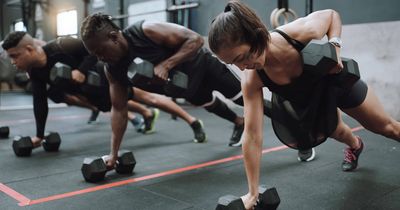 Frauen und Männer beim Training in Liegestützposition auf Hantel gestützt