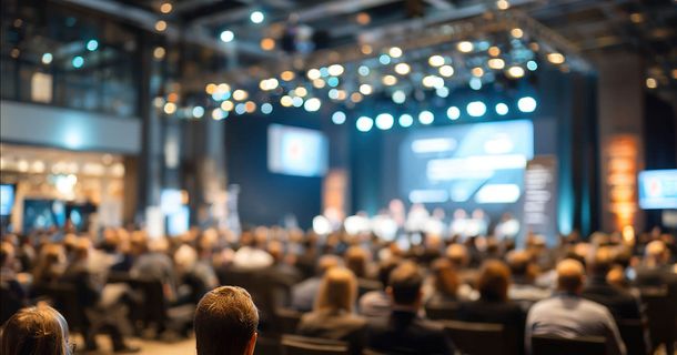 Menschen, die vor einer Kongressbühne sitzen