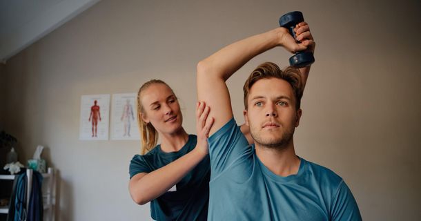Physiotherapeutin behandelt Schulter eines jungen Patienten