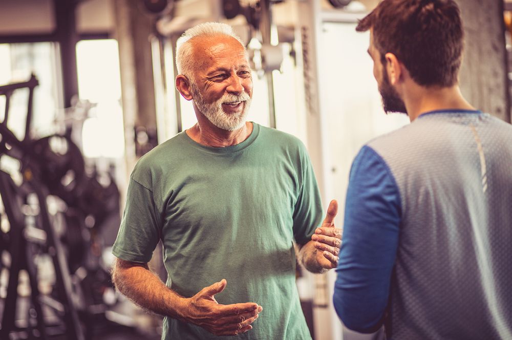 Mann redet mit seinem Fitnesstrainer im Fitnessstudio