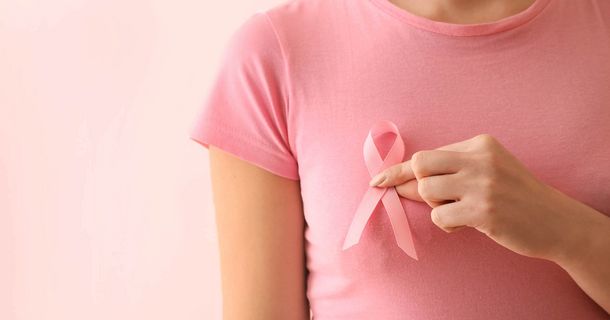 Frau hält Brustkrebs-Schleife vor die Brust, um auf Brustkrebs aufmerksam zu machen