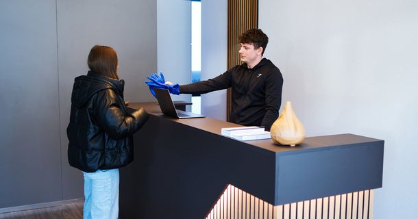 Frau an der Rezeption bei cooldown.me mit einem Hand von dem sie Handschuhe bekommt