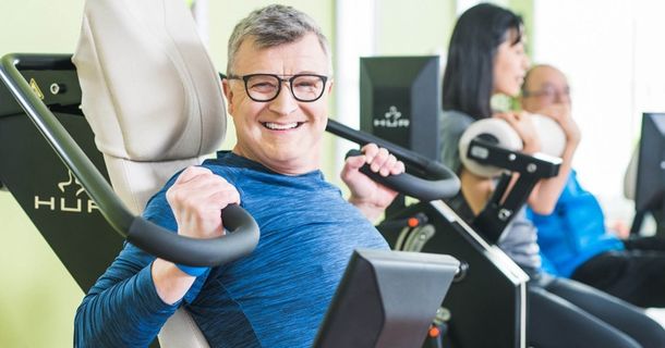 Mann trainiert an HUR-Trainingsgeräten und lächelt in die Kamera