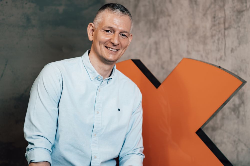 Markus Vancraeyenest, CEO der FitX Holding SE vor dem FitX Logo