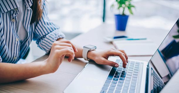 Frau sitzt vor einem Laptop und nimmt an Webinar teil