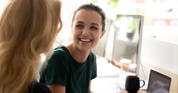 Eine Ausbilderin blickt zu einer lächelnden Auszubildenden 
