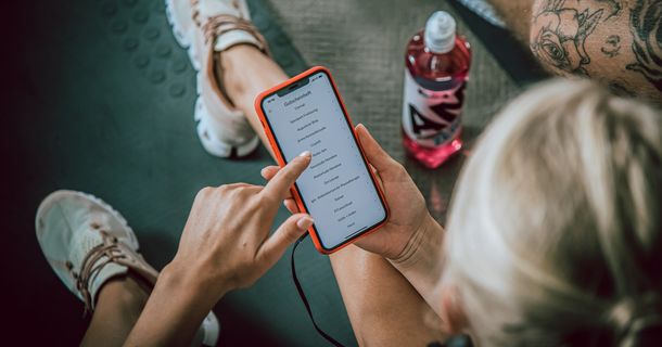 Fitnessstudiomitglied bedient MYGYM App auf ihrem Smartphone