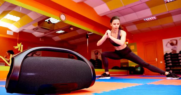 Musikbox im Fitnessstudio, im Hintergrund dehnt sich eine Frau