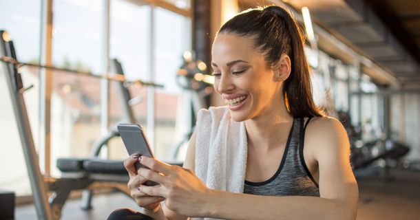 Fitnessstudiomitglied am Handy im Fitnessstudio