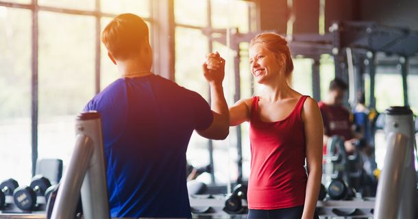 Fitnessstudiomitglied gibt seinem Trainer einen Handschlag auf der Trainingsfläche