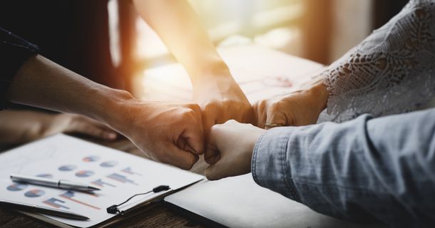 Mitarbeiter geben sich einen Fistbump, Symbolfoto Kooperation