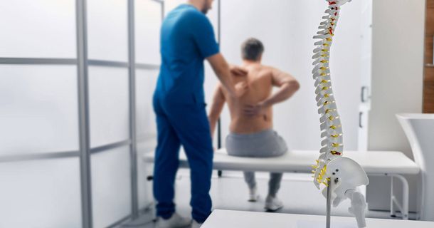 Physiotherapeut behandelt die rheumatoider Arthritis eines Patienten an der Wirbelsäule