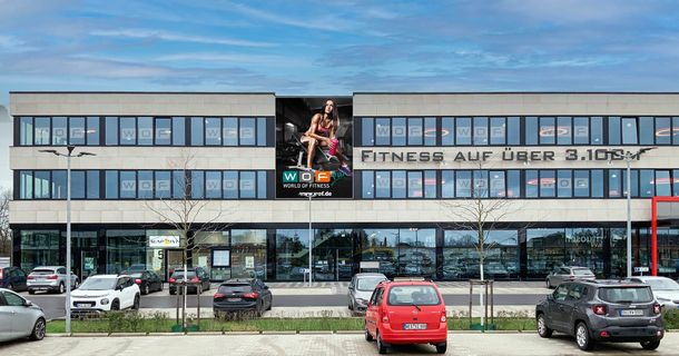 WOF-Fitnessstudio von Außen inklusive Parkplatz und einigen Autos
