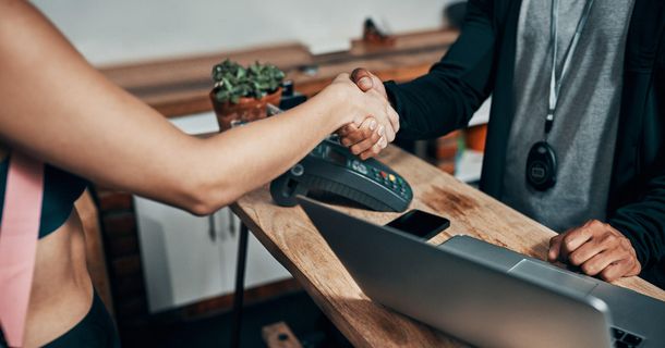 Fitnesscoach schüttelt die Hand eines Fitnessstudiomitglied