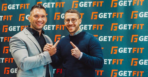 Eugen Leibman und Eckhard Santana mit erhobenem Zeigefinger vor einer GET FIT-Pressewand