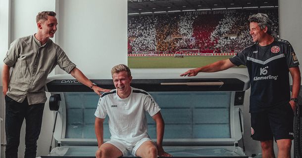 Sportdirektor Niko Bungert, Profispieler Jonathan Burkardt und Leiter Regenerations- und Prophylaxemanagement Steffen Tröster von Mainz 05 präsentieren ihr neues Ganzkörper-Rotlichtgerät (v. l.)